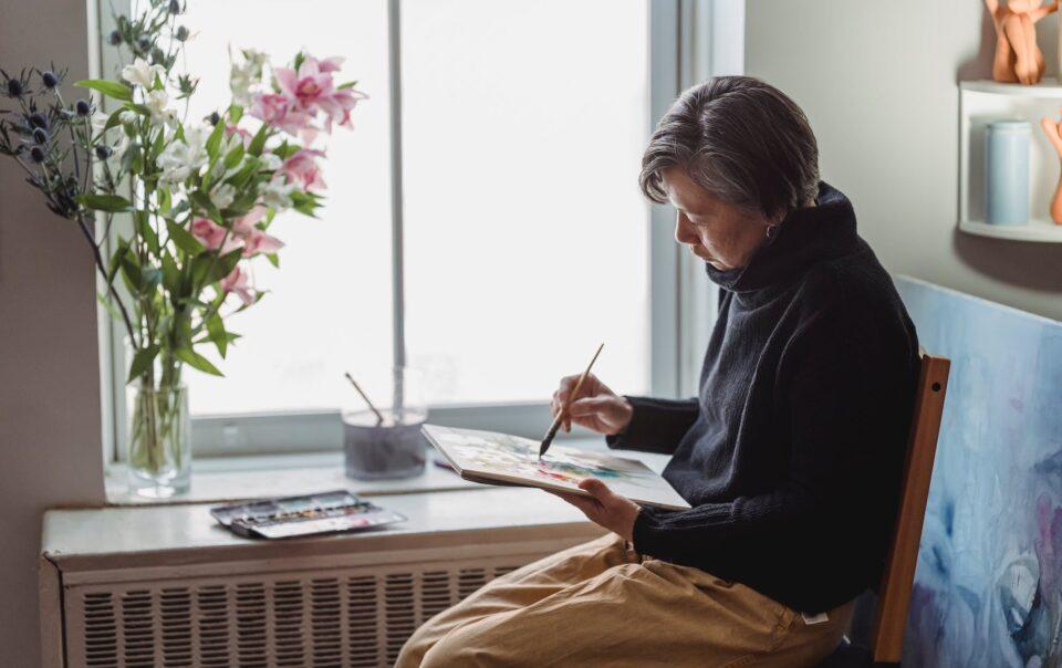 a woman painting an artwork in a sketchpad